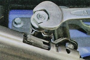 Опустите рычаг стояночного тормоза вниз до упора, полностью отверните и снимите с резьбового наконечника переднего троса контргайку