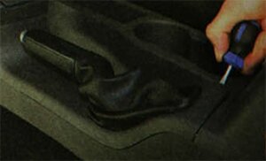 Подденьте отверткой край рамки чехла рычага привода стояночного тормоза