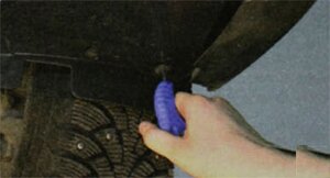 Выверните семь винтов крепления брызговика двигателя к нижней поперечине рамки радиатора и снимите брызговик.