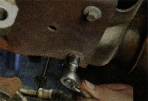 Выверните два болта крепления защитного щитка к катколлектору и блоку цилиндров двигателя