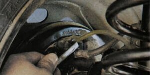 Наденьте резиновый шланг на клапан выпуска воздуха рабочего цилиндра тормозного механизма правого заднего колеса и погрузите конец шланга в чистый прозрачный сосуд